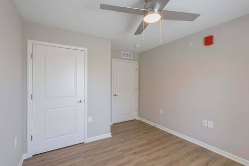 A room with a ceiling fan and two doors.