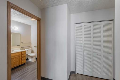 A white bathroom with a toilet, sink, and a white closet.