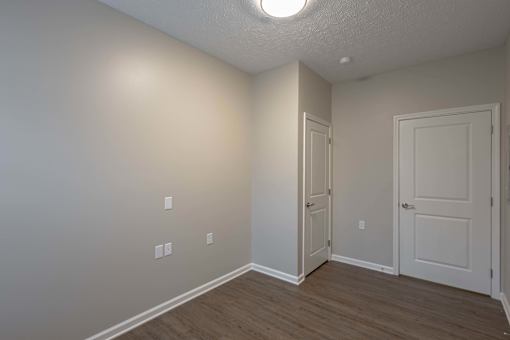 A room with a white door and a white wall with a light switch.