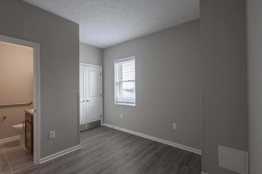 A room with a wooden floor and a window with blinds.