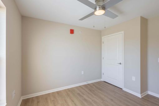 A room with a ceiling fan and a white door.