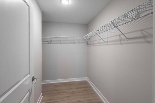 A white closet with a door and a shelf.