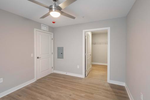 A room with a ceiling fan and a doorway leading to another room.