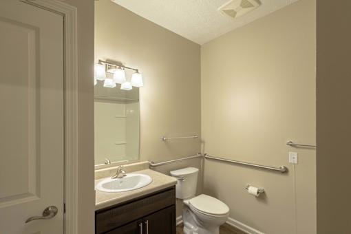 A bathroom with a toilet, sink, and mirror.