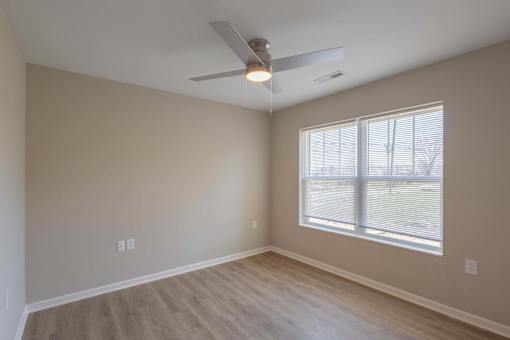 A room with a ceiling fan and a window with blinds.