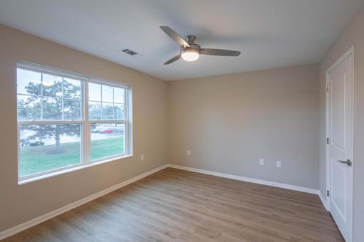 A room with a ceiling fan and a large window.