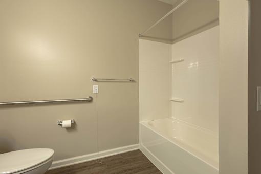 A white toilet sits next to a white bathtub in a bathroom.