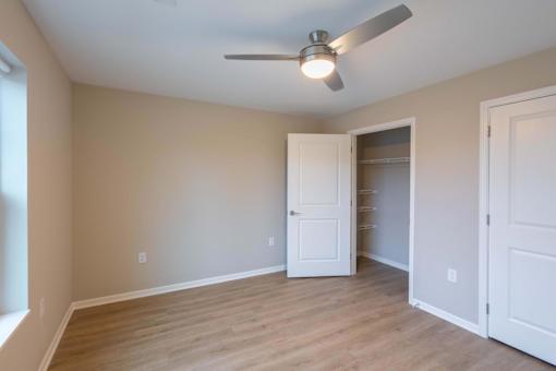 A room with a ceiling fan and a doorway leading to another room.