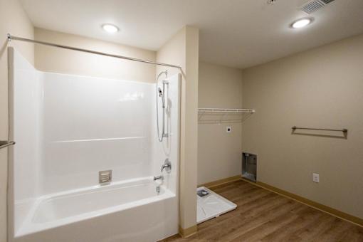 A white bathtub with a shower head and a white toilet in a bathroom.