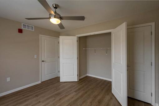 A room with a ceiling fan and a doorway leading to another room.