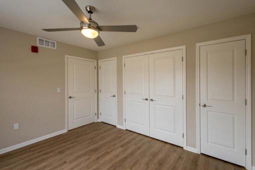 A room with a ceiling fan and four doors.