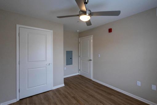A room with a ceiling fan and two doors.