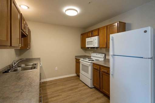A kitchen with a white refrigerator, sink, and stove.