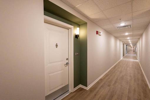 A long hallway with a white door and a green door.