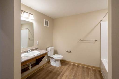 A bathroom with a toilet, sink, and mirror.