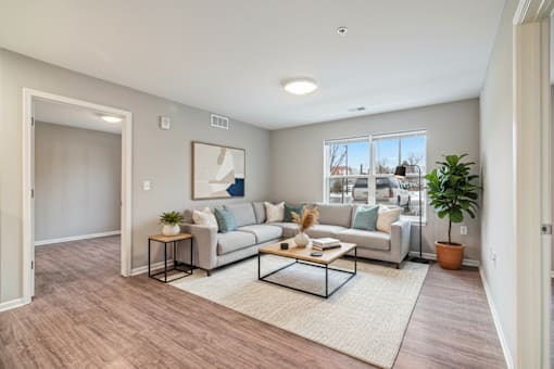 A living room with a grey couch, a coffee table, and a large window.