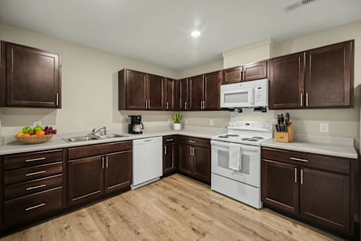 A kitchen with brown cabinets and white appliances.