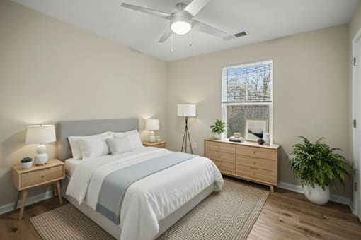 A bedroom with a bed, nightstands, and a plant.