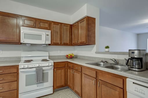 A kitchen with white appliances and wooden cabinets.