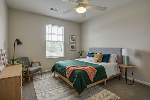 A bedroom with a bed, chair, and a ceiling fan.
