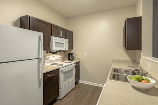 A kitchen with a white refrigerator, black cabinets, and a white countertop.