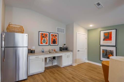 A kitchen with a refrigerator, a sink, and a dining table with chairs.