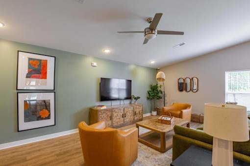 A living room with a television, orange armchair, and a green couch.
