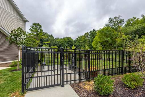 A black metal gate leads to a lush green yard.