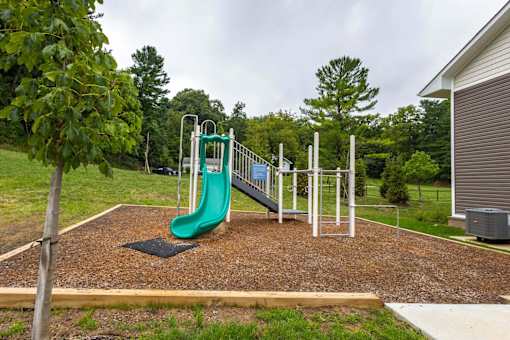 A playground with a green slide and a brown surface.