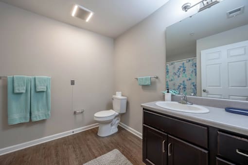 A bathroom with a toilet, sink, and towels.