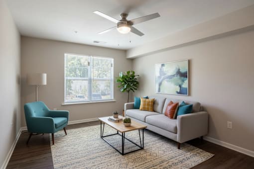 A living room with a blue chair, a grey couch, and a ceiling fan.