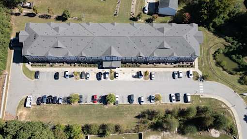 A large building with a grey roof is surrounded by a parking lot.