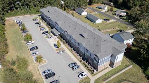A large grey building with a parking lot in front.