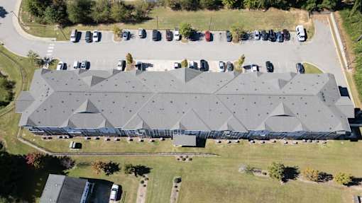 A large grey building with a grey roof and a parking lot in front.