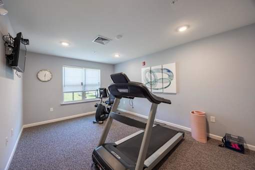 A treadmill is in a room with a clock on the wall.