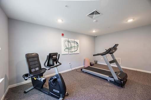A room with a treadmill and a stationary bike.