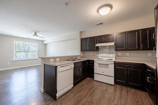 A kitchen with white appliances and dark wood cabinets.