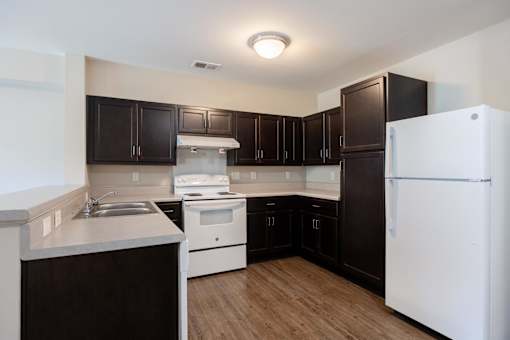A kitchen with white appliances and dark brown cabinets.