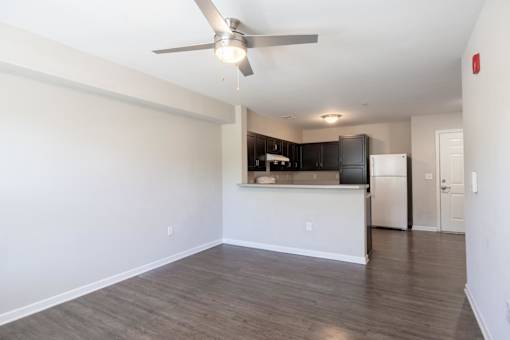 A spacious kitchen with a fan and a refrigerator.