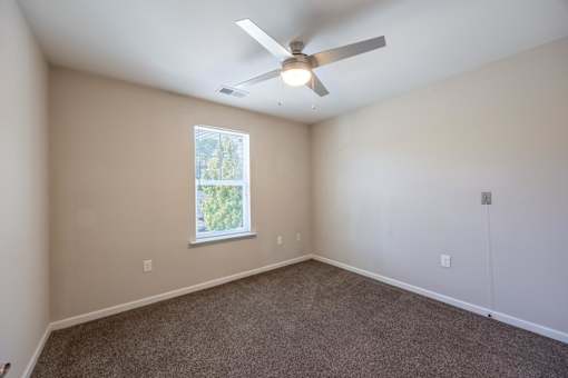 A room with a ceiling fan and a window.