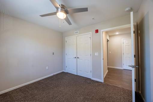 A room with a ceiling fan and carpeted floor.
