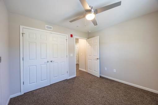 A room with a ceiling fan and carpeted floor.