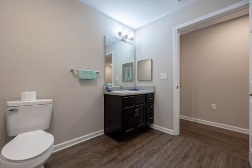 A bathroom with a toilet, sink, and mirror.