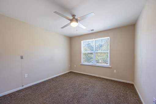 A room with a ceiling fan and a window.