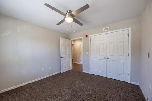 A room with a ceiling fan and carpeted floor.
