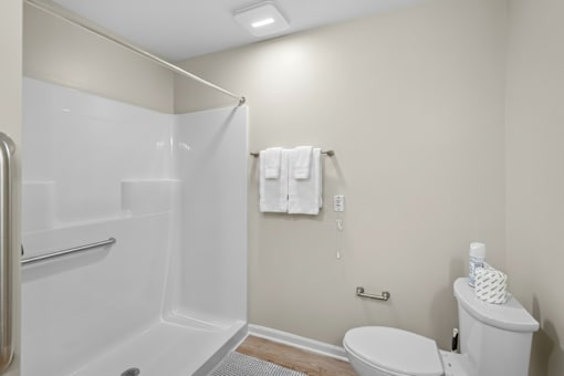 A white bathroom with a toilet, sink, and shower.