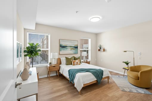 A bedroom with a bed, chair, and a painting on the wall.