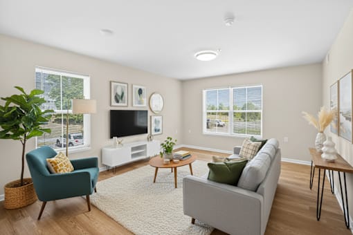 A living room with a grey couch, a blue armchair, a coffee table, and a television.