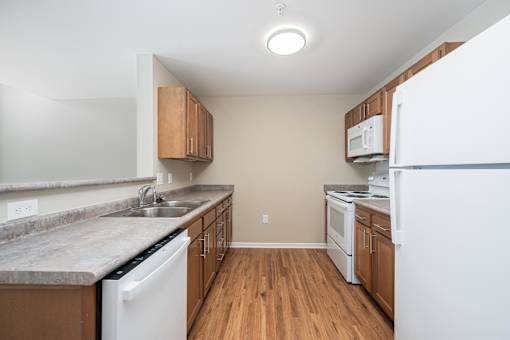 A kitchen with white appliances and wooden cabinets.