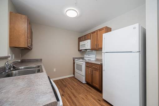 A kitchen with a white refrigerator, white oven, and white microwave.